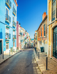 Fototapeta premium Typical narrow street with colorful multicolored traditional buildings and houses in Lisbon Lisboa historical city centre, Portugal.