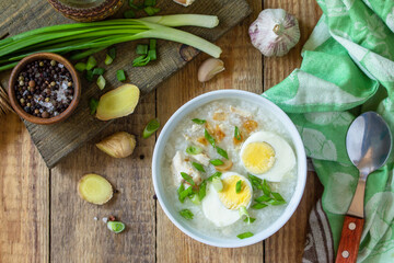 Hot soup chicken with ginger rice and garlic in a bowl on a rustic table. Top view flat lay.