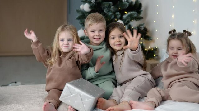 Children showing bye-bye near Christmas tree. Fashion for children concept