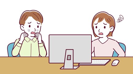 Two people talking while looking at a desktop computer