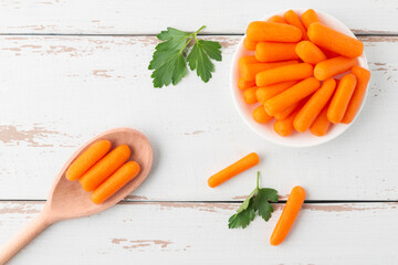 Small peeled pieces of carrot in plate on white wooden table. Top view.