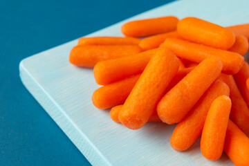 Peeled pieces of baby carrot on blue background