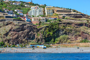 Ocean view of Funchal city. Volcanic formations in the foreground. In the foreground is the beach. Madeira island, Portugal, Europe.