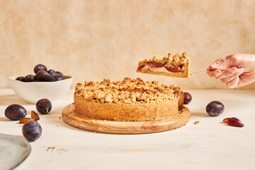 A closeup shot of a hand taking a slice of delicious plum cake