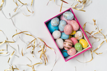 Gift box with colorful Easter eggs. White holiday background. Top view