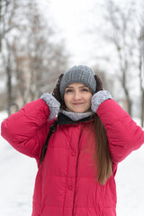 Portrait of girl in warm hat against background of winter park. Vertical frame