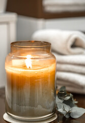 Spa composition with burning candle and bath towels close up.