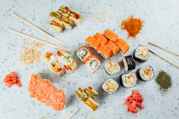 Close up view on assorted Japanese sushi food and rolls on bright table, chopsticks and ingredients