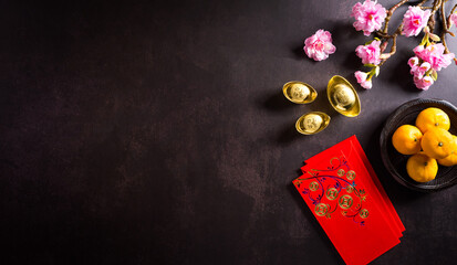 Chinese new year festival decorations pow or red packet, and gold ingots or golden lump on dark stone background. Chinese characters FU in the article refer to fortune good luck, wealth, money flow.