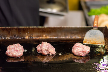 Chef cooking hamburgers.Kitchen employee preparing pork cutlets in hot oil.