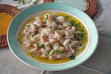 Plate with a carpaccio of raw scallops with citrus and olive oil