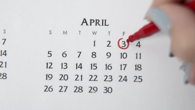 Female hand circle day in calendar date with a red marker. Business Basics Wall Calendar Planner and Organizer. APRIL 3th