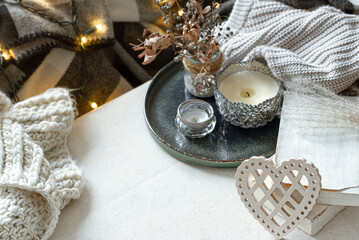 Cozy home composition with decorative wooden heart, candles and books.