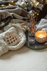 Cozy home composition with a burning candle and knitted elements.