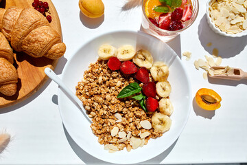 Healthy breakfast bowl, fresh granola, muesli berries strawberry, banana on white table in hard lights, Top view, Copy space. Clean eating, detox, dieting, vegetarian food concept