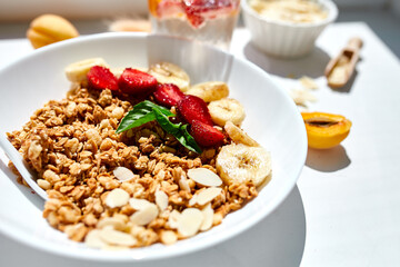 Healthy breakfast bowl, fresh granola, muesli berries strawberry, banana on white table in hard lights, Top view, Copy space. Clean eating, detox, dieting, vegetarian food concept