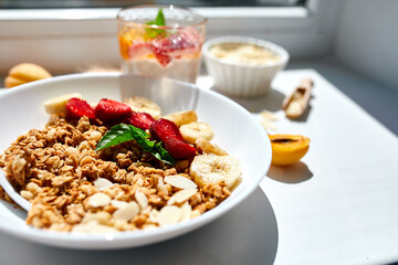 Healthy breakfast bowl, fresh granola, muesli berries strawberry, banana on white table in hard lights, Top view, Copy space. Clean eating, detox, dieting, vegetarian food concept