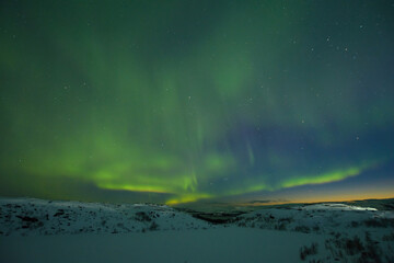 Naklejka na ściany i meble Northern lights in the sky. Snowy tundra at night.