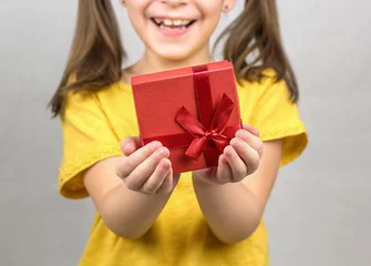 Cercles muraux Doux monstres Jeune fille souriante tenant une boîte cadeau rouge avec un noeud de ruban dans ses mains