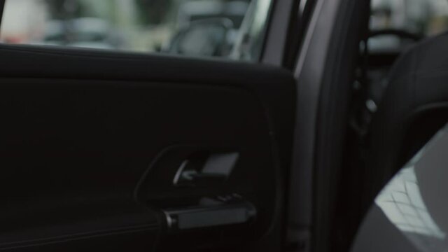 Close up slowmo of unrecognizable salesman or driver in formal attire opening car door for young woman