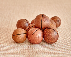 Macadamia nuts lie on a light brown surface.