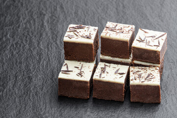 Chocolate brownie bites with sparklng chocolate topping on black stone background