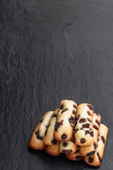 Sponge cake fingers with sultanas on black stone background