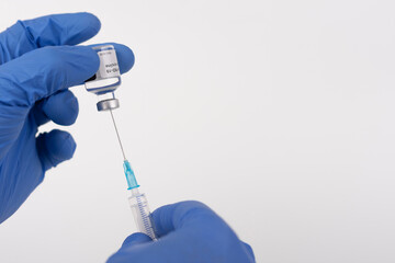 Close up human fingers in gloves, holding covid-19 vaccine vial and syringe with needle. Medical concept.