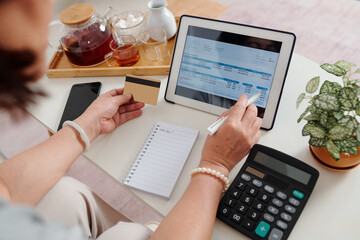 Hands of woman with credit card using application on tablet computer when paying utility bills