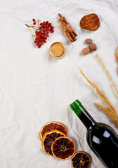 Flat lay of ingredients and bottle of red wine for winter seasonal mulled wine on white textile linen tablecloth, Still life, cloth texture background, Christmas drink, copy space.