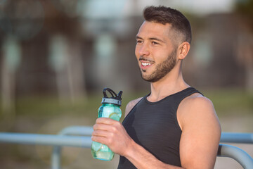 Man drinks water with lemon from reusable bottle during a workout. Drinking while exercising. Dehydration while training