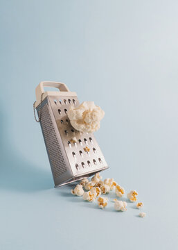 Minimal composition with grater, cauliflower and popcorn on pastel blue background. Transformation concept with copy space.