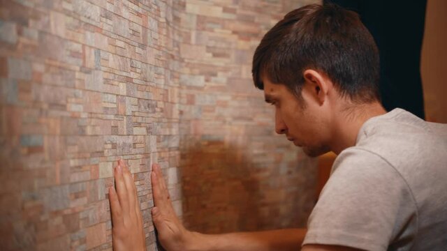 Serious man carefully glues wallpaper in a new house