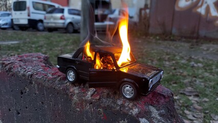 Children's car on fire. Lit children's toy car on the background of the playground. A dangerous...