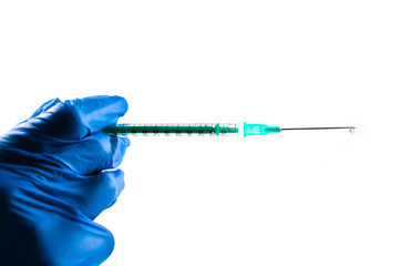 Syringe with a droplet in the hand of a doctor wearing blue gloves.  White background.  Copy space. Covid-19 vaccination.