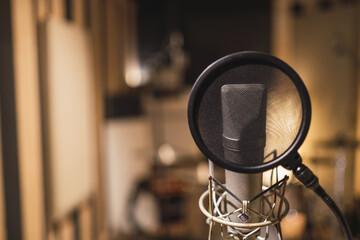 A selective focus shot of a pop filter and studio microphone, professional audio equipment