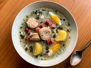 Traditional Polish soup Zurek with eggs, white and red sausages.