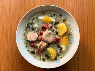 Traditional Polish soup Zurek with eggs, white and red sausages.