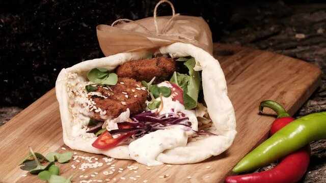 kebab, gyros, shawarma on a board, wrapped in paper. Rotates on a plate. Cyclic motion