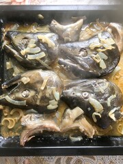 delicious homemade lunch - big fish heads baked with onions on a pan