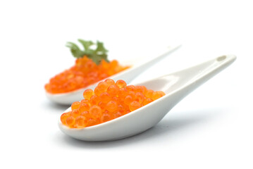 Closeup of trout eggs in a white ceramic spoon on white background