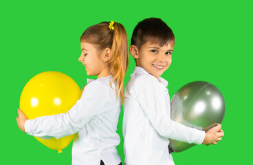 Fototapeta na wymiar Two happy preschool children with balloons on a green background. Illuminating and ultimate grey, 2021 trend color