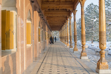 Monument of Memory with carved pillars in Uzbekistan on Independence square, against the background of Christmas trees covered with snow in winter