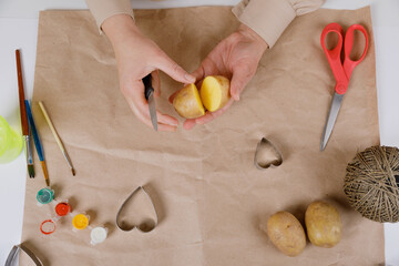 heart shaped potato stamp on craft paper. The process of decorating a gift for Valentine's Day. Getting ready for the celebration on February 14th.