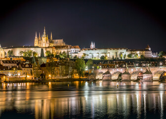 View of the city of Prague with St. Vitus Cathedral on the hill, Charles Bridge and the Vltava river at night