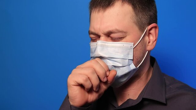 Sick man coughs heavily, hemoptysis hemorrhage spitting blood in saliva as a result of tuberculosis or lung cancer on a blue background. Open tuberculosis or severe pneumonia lung disease