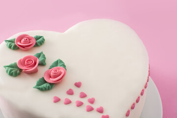Heart cake for St. Valentine's Day, Mother's Day, or Birthday, decorated with roses and pink sugar hearts on pink background	