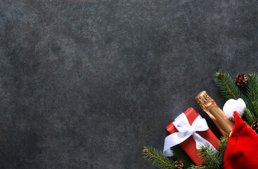 Background in New Year's concept. Decoration with fir, gifts with a bottle of champagne on a black...