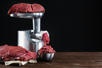 The process of cooking minced meat with a meat grinder on a black background