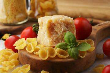 Piece of cheese, pasta, tomatoes on wooden board